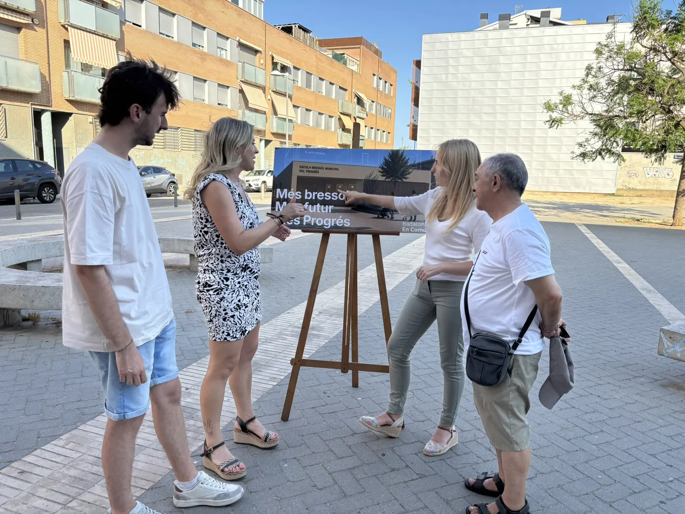 Veïnes i veïns del Progrés comentant el cartell de la futura escola bressol del barri